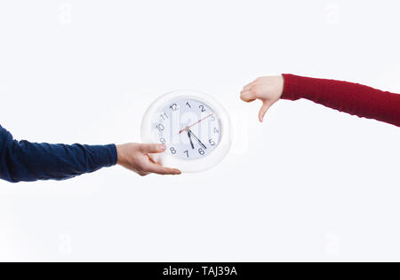 Mann, eine Uhr zu einer Frau mit einem Daumen nach unten Geste. Zeit-management und Planung Konzept. Planen Effizienz Metapher. Stockfoto