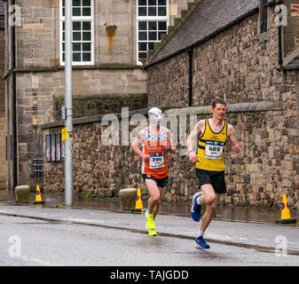 Holyrood, Edinburgh, Schottland, Vereinigtes Königreich. 26. Mai 2019. Edinburgh Marathon: Die Marathonläufer laufen an einem nassen Tag am Holyrood Palace vorbei. Grant Baillie (489) Running, der auf dem 32. Platz eine Wohltätigkeitsorganisation mit einer Laufmaske zugunsten der Wohltätigkeitsorganisation Muscle Dystrophy UK beendete Stockfoto