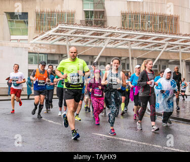 Holyrood, Edinburgh, Schottland, Vereinigtes Königreich. 26. Mai 2019. Edinburgh Marathon: Marathonläufer laufen an einem nassen Tag am schottischen Parlamentsgebäude vorbei. Stockfoto