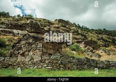 Rustikales Steinhaus und Wand auf hügeligen Landschaft mit Felsen und Büsche, in bewölkten Tag in der Nähe von Villa Covelo. Wie die Portugiesische Schweiz für ihre Landschaft bekannt Stockfoto