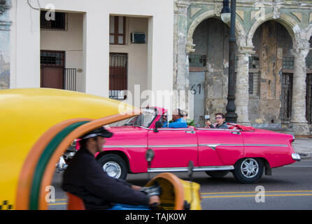 Havanna, Kuba - Ein amerikanisches Auto und eine Coco-Taxi auf dem Malecón Straße mit Blick auf Bucht von Havanna. Klassische amerikanische Autos aus den 50er Jahren importiert werden, bevor der US-e Stockfoto