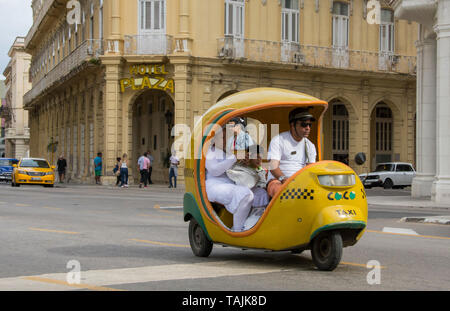 Havanna, Kuba - ein Dreirädriges Coco Taxi, so genannt, weil es wie eine Kokosnuss geformt ist, passiert vor Hotel Plaza in der Nähe von Parque Central. Stockfoto