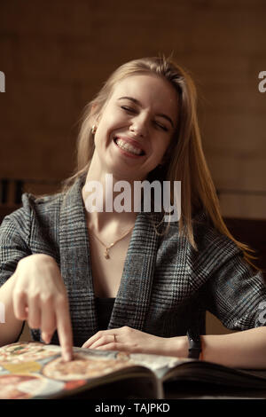 Glückliche junge Frau wählen Sie Pizza im Cafe Punkt den Finger auf Menü lachen Stockfoto