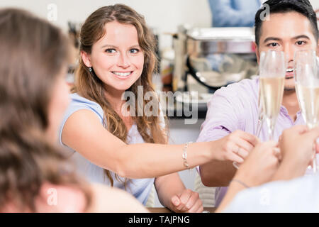 Lächelnden jungen Frau toasten Champagner Glas mit Freunden Stockfoto