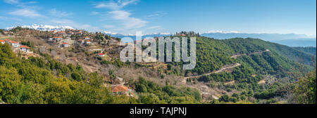 Panoramablick auf kleinen Bergstadt in der Griechischen Landschaft, mit schneebedeckten Bergen im Hintergrund. Ländliche griechische Weiler in den Hang. Stockfoto