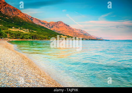 Sommer Urlaub und Strand. Beliebte Kiesstrand mit hohen Bergen im Hintergrund bei Sonnenuntergang, Brela, Makarska Riviera, Dalmatien, Stockfoto