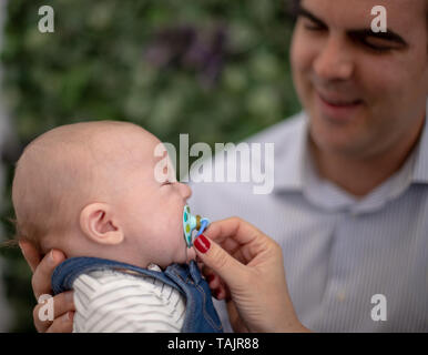 Der Vater versucht, sein Baby zu setzen, indem sie ihn aufrecht und in seine Arme, um zu schlafen. Stockfoto