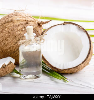 Kokosöl in Glas und Shell Stücke auf weiße Holztisch Stockfoto