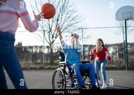 Teenager im Rollstuhl Basketball spielen mit Freunden Stockfoto