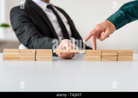 Unternehmer, die eine Brücke der Holz- Bausteine für seinen Partner in einem konzeptionellen Bild zu gehen. Stockfoto