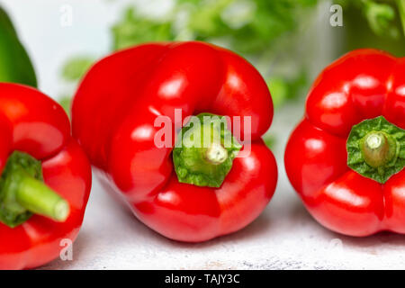 Drei rote Paprika mit Koriander im Hintergrund Stockfoto
