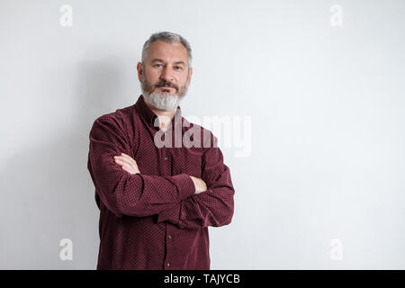 Brustbild eines schweren Grauhaarige bärtigen Mann in einem Burgund Shirt auf einem weißen Hintergrund. Stockfoto