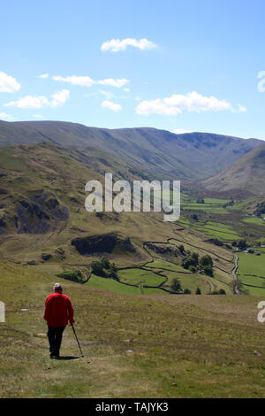 Lady in Red Jacket absteigend fiel Seite Pfad auf Hallin fiel, Lake District, Cumbria mit Blick Richtung Süden nach Martindale, Howe Korn und High Street. Stockfoto