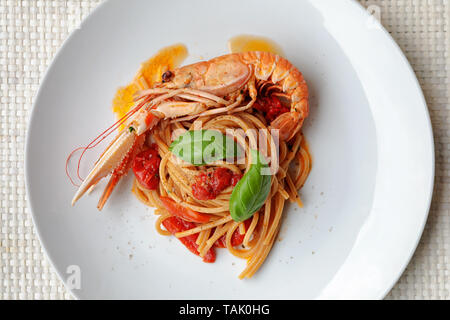 Nudeln mit Scampi Sauce, Kirschtomaten und Basilikum. Bereit zu essen. Spaghetti mit Scampi, Fisch essen. Stockfoto