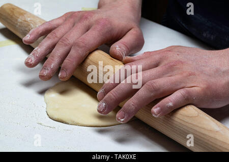 Ein junger Mann bereitet frische Tortillas mit einem Holz- Rolling Pin Stockfoto