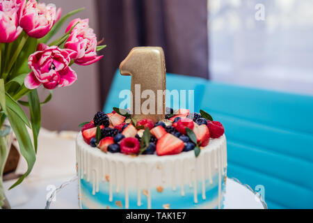Tabelle mit Süßigkeiten, Berry Kuchen 1 Jahr, Schokoriegel, leckere Süßigkeiten auf Süßigkeit Buffet, Kuchen mit frischen Beeren, Kinder Geburtstag. Der erste Geburtstag Kuchen Stockfoto