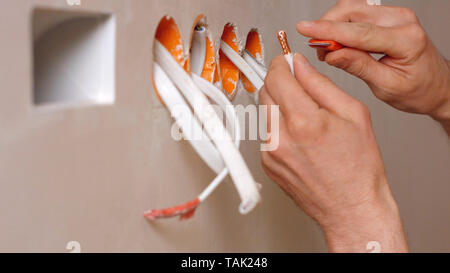 Elektriker arbeiten mit Kabel in der neuen Wohnung. Elektriker Hand, die elektrischen Kabel. Renovierung und Bau. Stockfoto