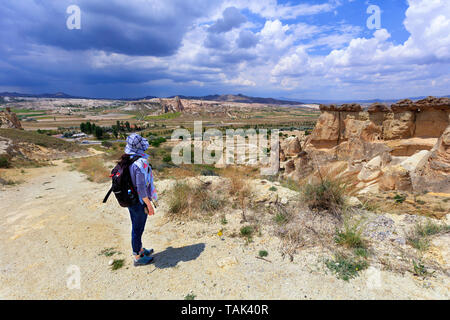 Ein junges Mädchen Tourist mit einem Rucksack auf dem Rücken steht am Rande einer Klippe in Kappadokien und bewundert die umgebenden Raum gegen die Backgr Stockfoto