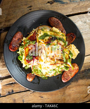 Frühstück ei Omelette mit Wurst, Spinat und Brot auf dem Teller auf hölzernen Tisch Set Stockfoto