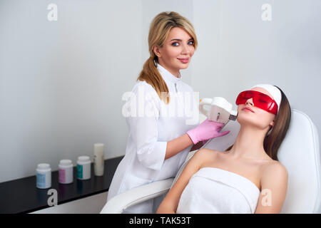 Kosmetikerin Arzt tun Laser RF Verjüngung für hübsche junge Frau Gesicht an Beauty Salon. Elos epilation Haarentfernung verfahren. Ästhetische Gesichts Stockfoto