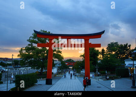 Sonnenuntergang an einem bewölkten Sommerabend an der großen Torii (Schrein Tor) an der Basis der Fushimi Inari Taisha Grand Schrein in Kyoto, Japan. Stockfoto