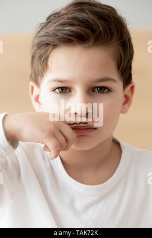 Portrait von kleinen Jungen halten Sie die Finger mit Schnurrbart Zeichnung Stockfoto