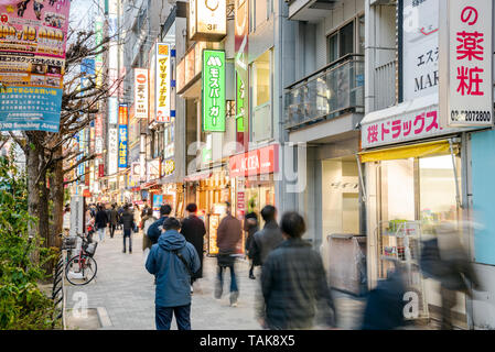 Tokyo, Japan - 23. März 2019: Menschen einen Bürgersteig entlang flanieren, gesäumt mit elektronischen Geschäfte und Restaurant in Akihabara Stockfoto