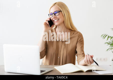 Reife Unternehmer per Telefon sprechen und Notizen Stockfoto