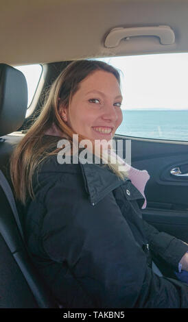 Junge 25 Jahre alt Frau sitzt im Auto und Lächeln Stockfoto