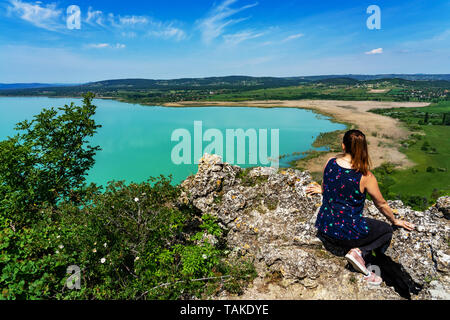 Arial Panoramablick auf den Balaton mit grossen Felsen Blumen und Reed auf Wanderweg mit einer jungen Frau genießt die Aussicht Stockfoto