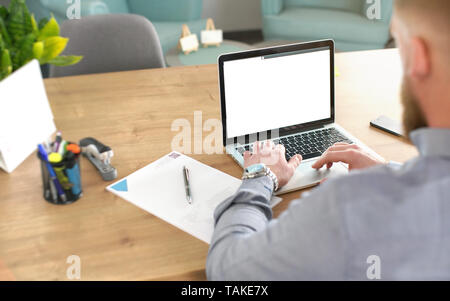 Anonyme Mann verschwommen aus wieder mit der Arbeit an seinem Laptop im Büro, Notepad, Markierungen und Kalender auf dem Schreibtisch, Ansicht von hinten, Detail auf Händen über Stockfoto
