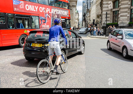 Ein Radfahrer ausweicht, der Verkehr an einer viel befahrenen Straße salbung vor der Royal Exchange Gebäude an der Bank in London, Großbritannien Stockfoto