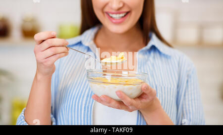 Mädchen essen Joghurt mit Flocken zum Frühstück Stockfoto