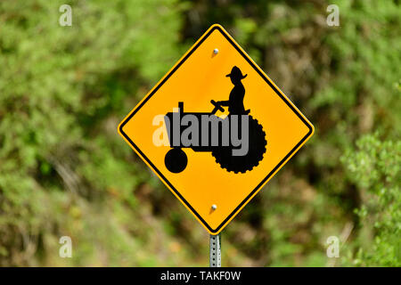 Ein horizontales Bild eines Schild Achtung Autofahrer, dass es vielleicht langsam fahrende landwirtschaftliche Maschinen auf der Straße Stockfoto