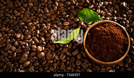 Schüssel mit frisch gemahlenem einzigen Ursprung Kaffee auf dem Hintergrund der gerösteten Bohnen mit grünen Blättern in einem Panorama banner Stockfoto