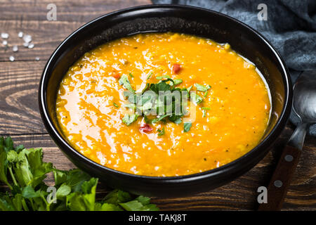 Rote Linsensuppe Püree in schwarz Platte auf dem Holztisch. Stockfoto