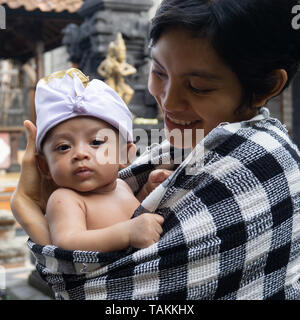 Das Porträt einer Mutter mit ihrem Baby, 3 Monate alt in der Mutter ist. Babys stellen mit typischen balinesischen Stirnbänder und die Mutter deckt sie Stockfoto