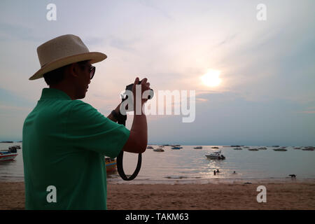 Der Mensch nimmt Fotos mit der Kamera am Strand Stockfoto