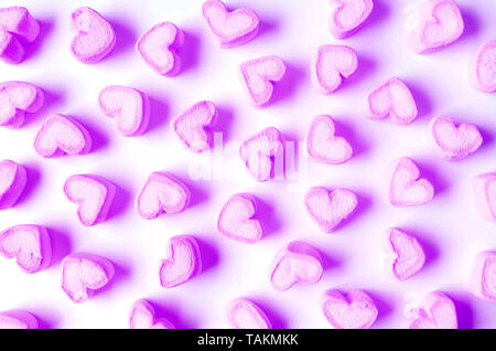 Lebendige und Pastell Lila Marshmallow Süßigkeiten in Herzform verstreut auf weißem Hintergrund Stockfoto