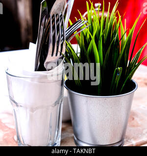 Außerhalb der Tabelle Einstellung mit einem künstlichen Pflanzen- und Essgeschirr in einem Glas Stockfoto