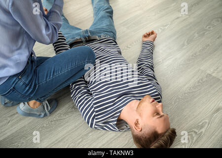 Frau Die erste Hilfe zu Ihrem unbewussten Mann zu Hause Stockfoto