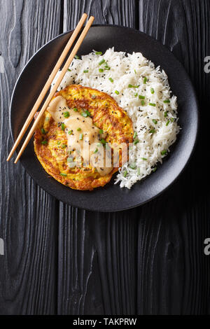 Knusprige flauschige Egg foo Junge gefüllt mit knackigen Gemüse und aromatische grüne Zwiebeln und serviert mit Reis close-up auf einem Teller. Vertikal oben Blick von abov Stockfoto