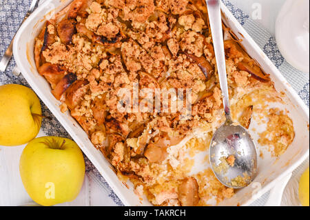 Apfelkuchen aus weisser Keramik Auflaufform. Hausgemachtes Frühstück mit Äpfeln. Helle Foto. Freier Platz für Text. Flach. Stockfoto