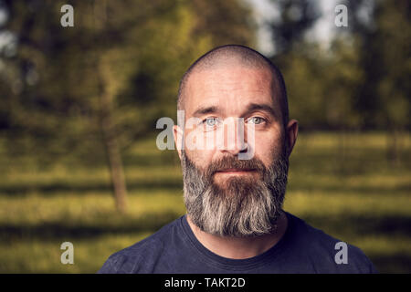 Ein weißer Mann über 43 Jahre alt, mit kurzen Haaren und Bart hat einen Rest in einem Park, close-up. Stockfoto