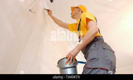 Builder Grundieren der Wand mit einem Pinsel in der neuen Wohnung. Vorbereitung der Wände streichen oder tapezieren. Home Restaurierung Konzept. Stockfoto