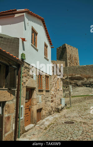 Altes, rustikales Haus vor der Mauer aus Stein und quadratischen Turm in Gournes. Ein mittelalterliches Dorf mit einzigartiger Architektur in Osteuropa Portugal. Stockfoto