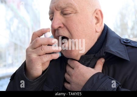 Älterer Mann mit Inhalator in Asthmaanfall im Freien Stockfoto