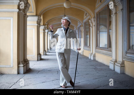 Ältere Frau in einem Anzug mit Hut mit einem Stock und eine Zigarette. Business Woman Stockfoto