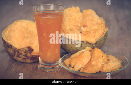 Arzneimittel Bael Frucht mit Saft in einem Glas auf Holz- Oberfläche Stockfoto