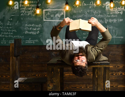 Erschöpft überforderten jungen Mann Studieren und Lesen Buch auf dem Tisch im Zimmer Stockfoto